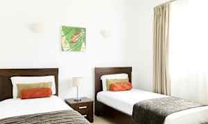 Værelse med to enkeltsenge, et natbord og vægdekoration. (AI-genereret tekst)