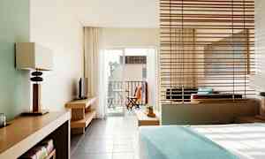 Et hotelværelse med moderne indretning og udsigt til en altan med havemøbler. (AI-genereret tekst)