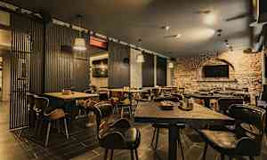 En restaurant med træborde og stole samt murstensvægge. (AI-genereret tekst)