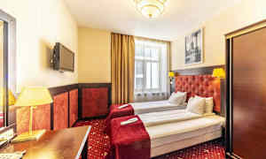 Hotelværelse med to enkeltsenge, røde sengetæpper og lamper. (AI-genereret tekst)