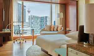 Et moderne hotelværelse med vinduer, der viser udsigt over en by, herunder en tårnkonstruktion. (AI-genereret tekst)