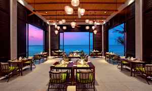 Billede af en restaurant med havudsigt og farverig aftenshimmel. (AI-genereret tekst)