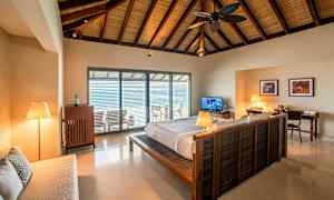 Interiør af et soveværelse med en dobbeltseng og et åbent vindue mod en altan. (AI-genereret tekst)