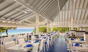 Udendørs restaurant med hvide møbler og havudsigt. (AI-genereret tekst)