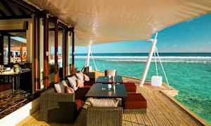 Udendørsterrasse med siddepladser, borde og udsigt over havet. (AI-genereret tekst)