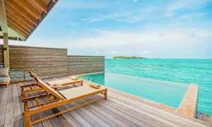 Terrasse med to solsenge ved en infinitypool og udsigt over turkisblåt hav. (AI-genereret tekst)