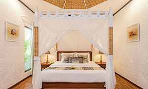 Et soveværelse med en himmelseng og dekorative puder. (AI-genereret tekst)