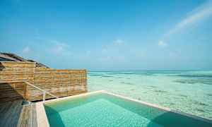 Swimmingpool ved havet med træhegn og klar blå himmel. (AI-genereret tekst)