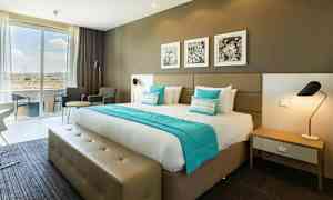 Hotelværelse med en dobbeltseng, siddeområde og store vinduer. (AI-genereret tekst)