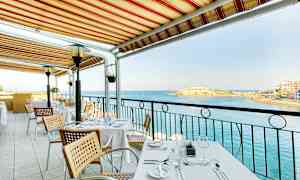 Et bord på en udendørsterrasse under en markise med udsigt over havet. (AI-genereret tekst)