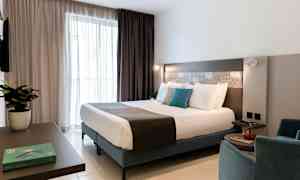 Et moderne hotelværelse med en dobbeltseng, siddepladser og indretningsdetaljer. (AI-genereret tekst)