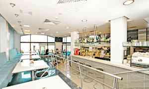 Et moderne caféinteriør med siddepladser og en bardisk. (AI-genereret tekst)