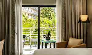 Hotelværelse med udsigt til en frodig altan. (AI-genereret tekst)