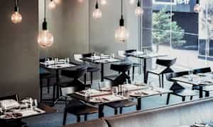 En moderne restaurant med elegant dækkede borde og hængende elpærer. (AI-genereret tekst)