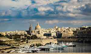 Udsigt over en by med en kuppelformet bygning og både i en havn. (AI-genereret tekst)