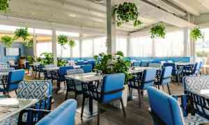 En restaurantinteriør med blå stole og grønne planter. (AI-genereret tekst)