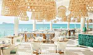 En lys restaurant med rottinglamper og udsigt over havet. (AI-genereret tekst)