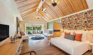 Et elegant hotelværelse med seng, siddeområde og udsigt til haven gennem skydedøre. (AI-genereret tekst)