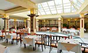 En rummelig restaurant med store vinduer og borde med hvide duge. (AI-genereret tekst)