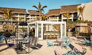 En udendørsbar med siddepladser på en sandstrand foran et hotel. (AI-genereret tekst)