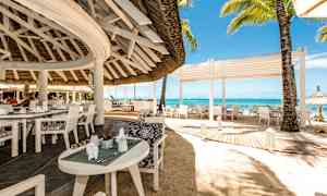 En åben restaurant ved stranden med hvide møbler og udsigt over havet. (AI-genereret tekst)