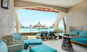 En terrasse med blå siddepladser og udsigt over havet med parasoller. (AI-genereret tekst)