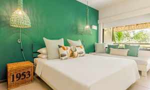 Et soveværelse med grøn væg, hvid seng og dekorative puder. (AI-genereret tekst)