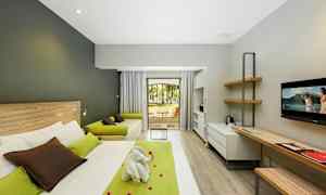 Moderne hotelværelse med seng, skrivebord, sofa og udsigt til en have. (AI-genereret tekst)