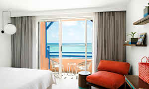 Et hotelværelse med en balkon, der har udsigt over havet. (AI-genereret tekst)