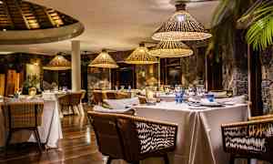 En elegant restaurant med dækkede borde og rottinglamper. (AI-genereret tekst)