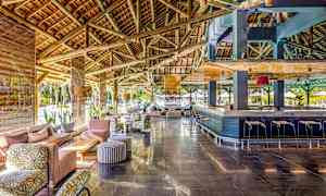 Rummelig lounge med træbjælker i loftet, siddegrupper og en bar. (AI-genereret tekst)