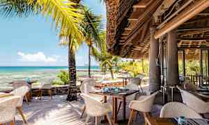 En strandrestaurant med siddepladser udendørs og udsigt over havet. (AI-genereret tekst)