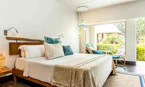 Et lyst soveværelse med en dobbeltseng og store vinduer ud mod en frodig have. (AI-genereret tekst)