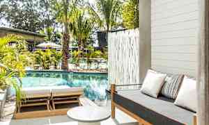 Udendørsområde med pool, solsenge og en sofa med puder. (AI-genereret tekst)