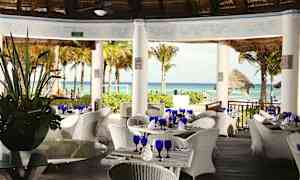 Restaurant med hvide flettede møbler under tag med udsigt over havet og palmer. (AI-genereret tekst)