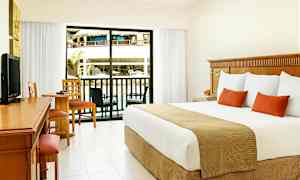 Hotelværelse med stor seng, skrivebord og siddeområde. Glasdør fører til en balkon med udsigt over poolområdet. (AI-genereret tekst)