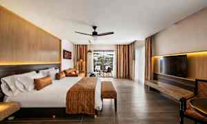 Hotelværelse med stor seng, siddeområde og udsigt gennem glasdøre. (AI-genereret tekst)