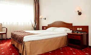 Hotelværelse med en seng, natbord og gardiner. (AI-genereret tekst)