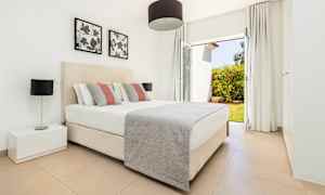 Et soveværelse med en dobbeltseng, natbord og vindue med udsigt til en have. (AI-genereret tekst)