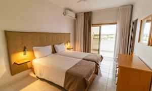 Et hotelværelse med to enkeltsenge, en kommode og en udgang til en altan. (AI-genereret tekst)