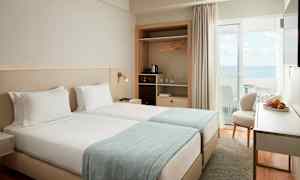 Et hotelværelse med to enkeltsenge og havudsigt. (AI-genereret tekst)