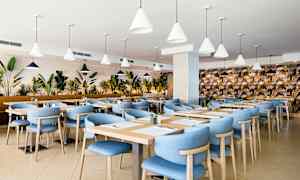 Restaurant med blå stole og træborde, omgivet af planter. (AI-genereret tekst)