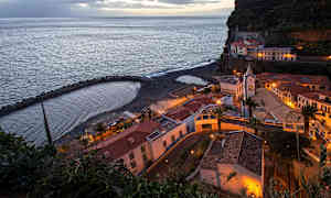 En kystby med bygninger og en lille strand under aftenstid. (AI-genereret tekst)