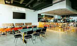 Restaurantinteriør med borde, stole og en bardisk. (AI-genereret tekst)