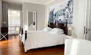 Et hotelværelse med to enkeltsenge, trægulv og et stort vægmaleri. (AI-genereret tekst)