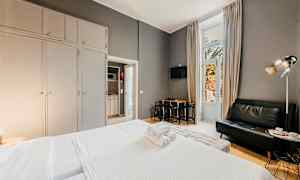 Hotelværelse med seng, sofa og spisebord, store garderobeskabe samt en altandør. (AI-genereret tekst)