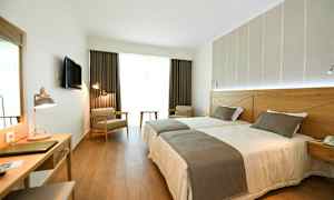 Hotelværelse med to enkeltsenge, skrivebord og siddepladser. (AI-genereret tekst)