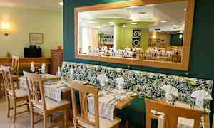 Restaurant med borde og stole samt spejl på væggen. (AI-genereret tekst)