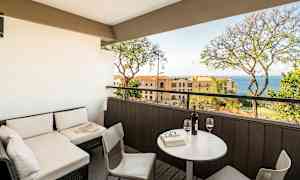 En terrasse med siddeområde og udsigt mod havet, med bord og to glas vin. (AI-genereret tekst)