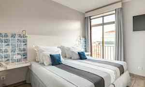 Et hotelværelse med to senge, blå dekorative puder og en vinduesudsigt. (AI-genereret tekst)